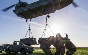 Militairen trainen met ladingen onder een helikopter.
